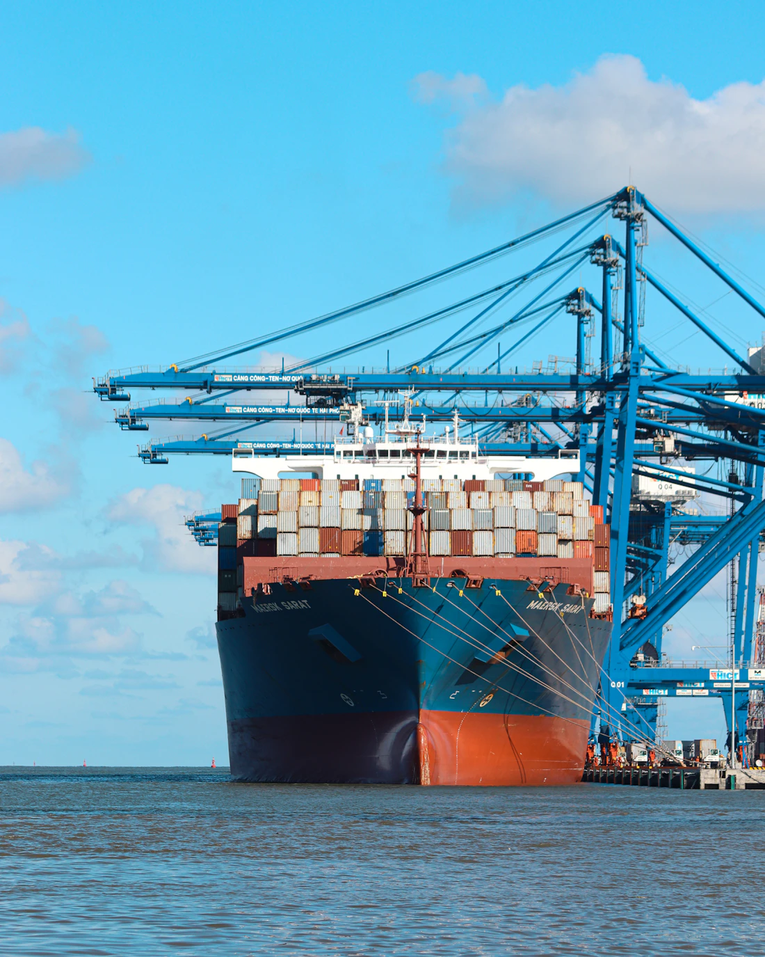 Container ship being loaded under gantry cranes at a working port
